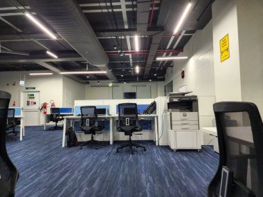 Hyderabad, India- 23 Aralık 2022; Mavi renkli ahşap döşemeli, bilgisayar masalı, sandalyeli ve açık tavan dizaynlı güzel ofisin resmi. Ofis içi .