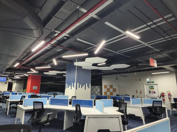 Hyderabad, India- 23 Aralık 2022; Mavi renkli ahşap döşemeli, bilgisayar masalı, sandalyeli ve açık tavan dizaynlı güzel ofisin resmi. Ofis içi .