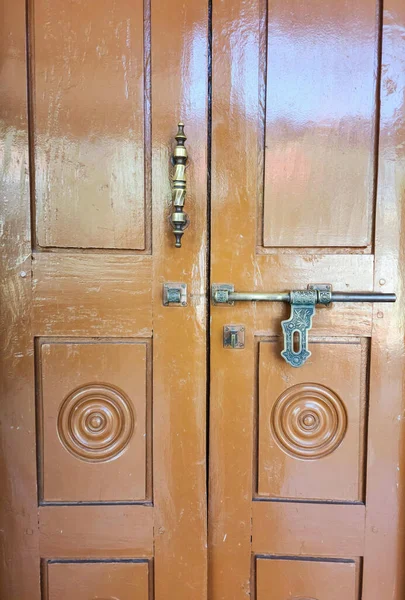 Stock photo of antique Indian style designer bronze metal aldrop door lock on brown color painted wooden door,Picture captured under natural light at Gulbarga, Karnataka, India. focus on object.