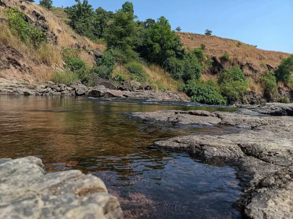 stock image stock photo of a beautiful natural water pond near Paleshwar Waterfall, adorned with calm and clean water, and surrounded by majestic mountains and lush green trees. Picture captured at Malkapur.