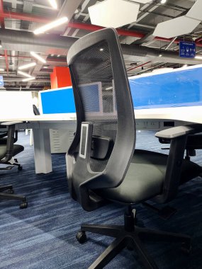 Hyderabad, India- 23 Aralık 2022; Arkaplanda bir bilgisayar masası ve diğer iç mekan eşliğinde siyah-sırt sırtı ergonomik bir masa başı metal tabanının stok fotoğrafı.