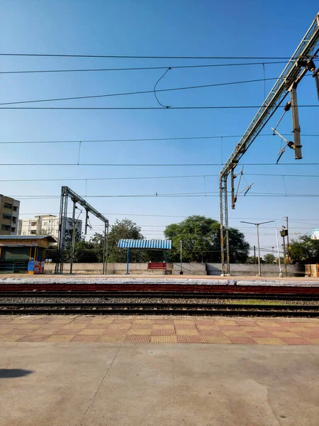 2022年12月17日インドのハイデラバード明るい日差しの下 赤い空の木製のベンチがあり 近くには閉鎖されたスナックセンターと鉄道線路が遠くに伸びていました — ストック写真