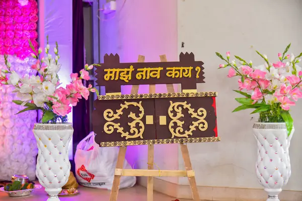 Kolhapur, Hindistan - 17 Mart 2024; Kahverengi ve altın renkli güzel bir dikdörtgen isim panosu gösteriyor ki benim adım ne? Marathi dilinde. Arkaplan isim töreni için süslemelerle süslenmiş. .