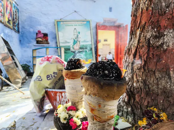 Gulbarga, Hindistan- 13 Şubat 2024 Yanan tütsü topakları ve közleri kırsal, ipliğe sarılı toprak tutacağında parlıyor. Duman perdesi bulanık duvara karşı yükseliyor.