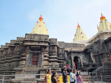 Kolhapur, Hindistan - 6 Kasım 2023, Kolhapur 'daki Mahalaxmi Tapınağı' nın antik taş mimarisi, karmaşık bir şekilde oyulmuş duvarlar ve altın kuleler, tapınak bölgesinde yürüyen ve giren fanatikler.