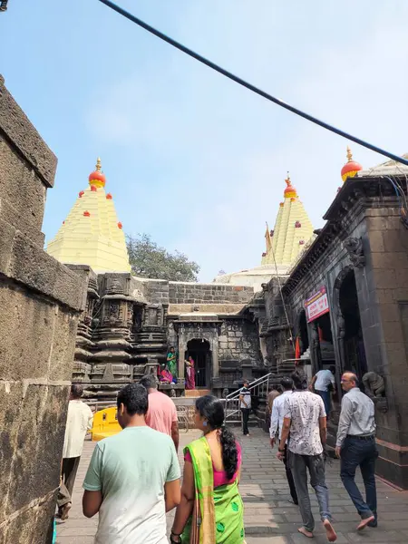 Kolhapur, Hindistan - 6 Kasım 2023, Kolhapur 'daki Mahalaxmi Tapınağı' nın antik taş mimarisi, karmaşık bir şekilde oyulmuş duvarlar ve altın kuleler, tapınak bölgesinde yürüyen ve giren fanatikler.