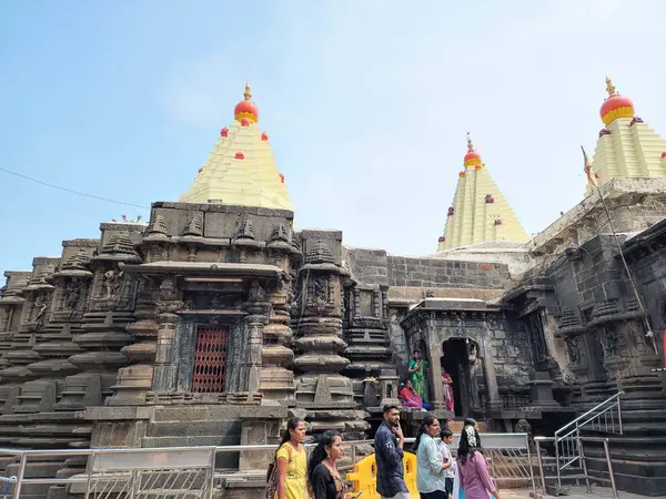 Kolhapur, Hindistan - 6 Kasım 2023, Kolhapur 'daki Mahalaxmi Tapınağı' nın antik taş mimarisi, karmaşık bir şekilde oyulmuş duvarlar ve altın kuleler, tapınak bölgesinde yürüyen ve giren fanatikler.