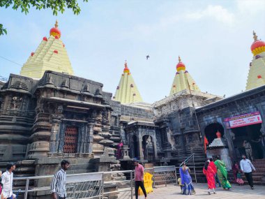 Kolhapur, Hindistan - 6 Kasım 2023, Kolhapur 'daki Mahalaxmi Tapınağı' nın antik taş mimarisi, karmaşık bir şekilde oyulmuş duvarlar ve altın kuleler, tapınak bölgesinde yürüyen ve giren fanatikler.