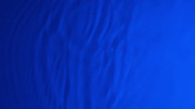 Damlalar, sıçramalar ve dalgalarla Neon Blue Water gradyan dokusu. Organik su, hafif yavaş çekim video pankartıyla donanma mavisi rengine bürünmüştür..