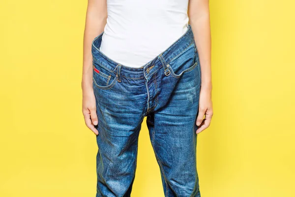 Slim Woman Showing Loose Jeans Her Loss Weight Isolated Yellow — Stock Photo, Image