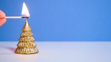 Mavi arka planda yanan altın Noel ağacı mumu bir mum yakar. Kopya alanı olan yeni yıl veya noel videosu pankartı.