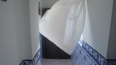 Açık bir pencere ve eski bir Portekiz evinde rüzgarda esen perdenin güzel atmosferik videosu. 4K çözünürlüklü iç görüntü.