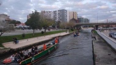 Aveiro, Portekiz - 02.12.2022: Portekiz 'deki Ria de Aveiro kentsel su kanalını turistlerle geçen Aveiro Moliceiro turistik tur teknesinin üst görüntüsü. Aveiro 'daki turist teknesiyle ilgili 4K çözünürlük videosu