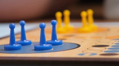 People play Ludo or Pachisi board game on beautiful wooden play board. Ludo is a strategy board game for two to four players. 4K resolution family board game video.
