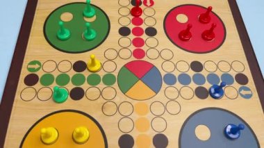 People play Ludo or Pachisi board game on beautiful wooden play board. Ludo is a strategy board game for two to four players. 4K resolution family board game video.