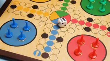 People play Ludo or Pachisi board game on beautiful wooden play board. Ludo is a strategy board game for two to four players. 4K resolution family board game video.