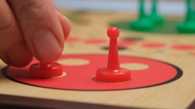 People play Ludo or Pachisi board game on beautiful wooden play board. Ludo is a strategy board game for two to four players. 4K resolution family board game video.
