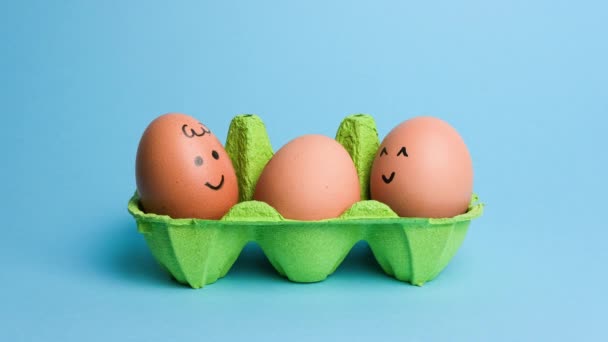 Милі Великодні Яйця Кумедними Обличчями Зеленій Коробці Ізольовані Синьому Фоні — стокове відео