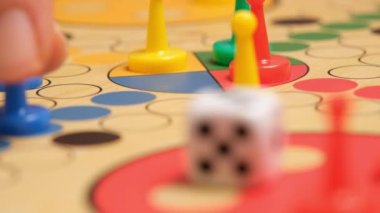 People play Ludo or Pachisi board game on beautiful wooden play board. Ludo is a strategy board game for two to four players. 4K resolution family board game video.