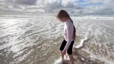 Çocuklar Atlantik Okyanusu kıyısı boyunca koşar. İki küçük kız kardeş Atlantik Okyanusu sahilinde dalgalarla oynuyorlar. Aile zamanı ya da tatil konsepti. 4K çözünürlük videosu.