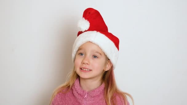 一个戴着红色圣诞老人帽的金发小女孩正在积极地讲述一些事情 并看着摄像机 这个女孩唱或朗诵一首诗 视频肖像 4K分辨率视频 — 图库视频影像
