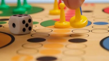People play Ludo or Pachisi board game on beautiful wooden play board. Ludo is a strategy board game for two to four players. 4K resolution family board game video.