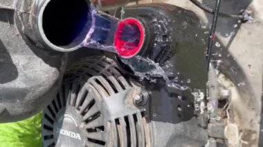Veiros, Portekiz - 11.05.2023: Koruyucu eldivenlerdeki eller eski bir Honda çim biçme makinesine benzin veya yakıt döker.