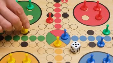 People play Ludo or Pachisi board game on beautiful wooden play board. Ludo is a strategy board game for two to four players. 4K resolution family board game video