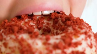 Mutlu bir şekilde çörek yiyen bir çocuğun yakın plan görüntüsü. Bir çocuk donut yiyor. Fast food ve sağlıksız yemek. 4K çözünürlük videosu