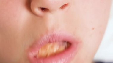 Mutlu bir şekilde çörek yiyen bir çocuğun yakın plan görüntüsü. Bir çocuk donut yiyor. Fast food ve sağlıksız yemek. 4K çözünürlük videosu