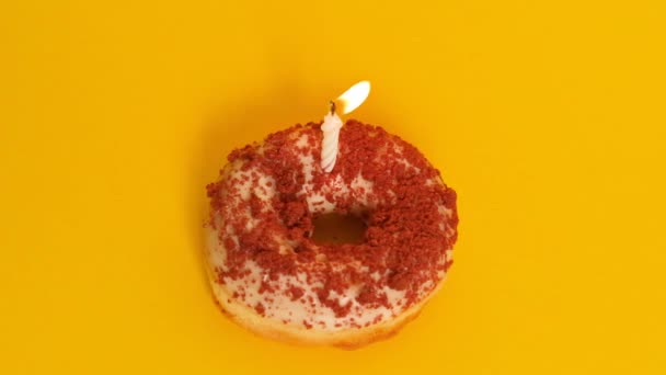 一只漂亮的甜甜圈 有一根燃烧的蜡烛 背景是黄色的 生日或结婚纪念日的蜡烛被吹灭了 生日快乐 — 图库视频影像