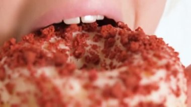 Mutlu bir şekilde çörek yiyen bir çocuğun yakın plan görüntüsü. Bir çocuk donut yiyor. Fast food ve sağlıksız yemek. 4K çözünürlük videosu