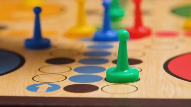People play Ludo or Pachisi board game on beautiful wooden play board. Ludo is a strategy board game for two to four players. 4K resolution family board game video