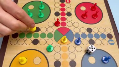 People play Ludo or Pachisi board game on beautiful wooden play board. Ludo is a strategy board game for two to four players. 4K resolution family board game video