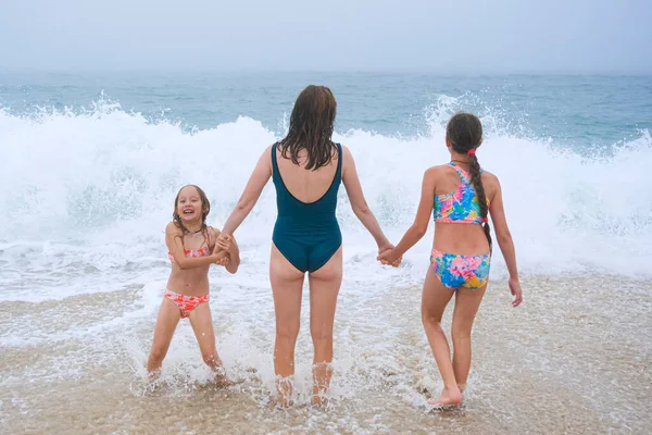海のビーチで遊んでいるお母さんと子供たち 家族は海を楽しんでいる 母は少女の手を握り みんなが一緒に海を見ている — ストック写真