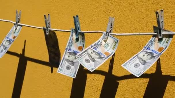 ドル紙幣はロープにぶら下がって 布地やフラッターにぶら下がる お金は黄色い壁の背景に風の中で泳いでいる マネーロンダリングの概念 — ストック動画