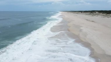 Atlantik Okyanusu ve deniz köpüğünün güzel mavi dalgaları üzerindeki hava aracı görüntüsü. Sonsuz deniz mavisi veya turkuaz deniz veya okyanus suyu ve plaj manzarası ve yaz günü sarı kum manzarası