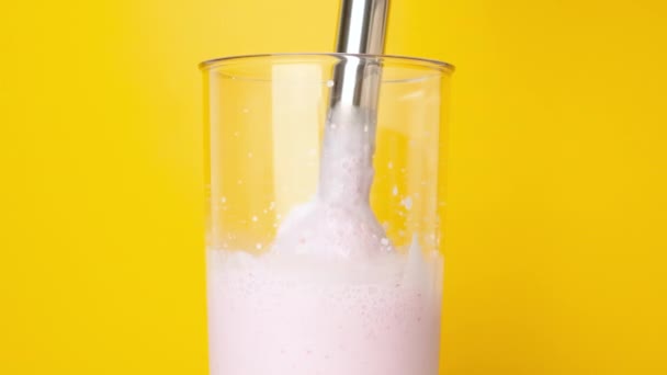 搅拌器搅拌牛奶 浆果和冰淇淋 在明亮的黄色背景下 搅拌机把红色浆果和冰淇淋牛奶倒入自制的奶昔中 — 图库视频影像