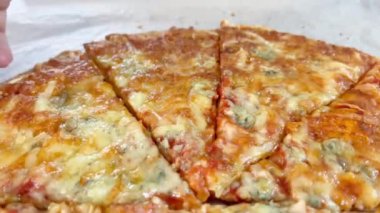 Hand 'in pizza kutusundan bir dilim pizza alırken yakın plan görüntüsü. Tek parça olmadan dört peynirli pizza. Kesik pizzanın üst görüntüsü. İtalyan yemeği, sokak yemeği, fast food, fast food