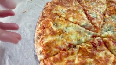 Hand 'in pizza kutusundan bir dilim pizza alırken yakın plan görüntüsü. Tek parça olmadan dört peynirli pizza. Kesik pizzanın üst görüntüsü. İtalyan yemeği, sokak yemeği, fast food, fast food