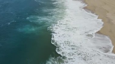 Atlantik Okyanusu ve deniz köpüğünün güzel mavi dalgaları üzerindeki hava aracı görüntüsü. Sonsuz deniz mavisi veya turkuaz deniz veya okyanus suyu ve plaj manzarası ve yaz günü sarı kum manzarası