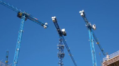 Lizbon, Portekiz - 22.12.2023: Mavi gökyüzüne karşı çalışan inşaat vinçlerinin görüntüsü. Lizbon, Portekiz 'de inşaat vinçleri olan bir inşaat sahası
