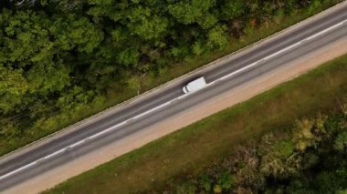 Çapraz insansız hava aracı ya da hava manzaralı raylar ve ağaçlar arasındaki yolda giden arabalar. 4K çözünürlük videosu İnsansız hava aracı ormandaki işlek bir yolun üzerinde süzülüyor..