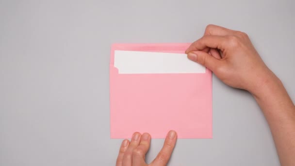 Hand Pulls Out White Card Bright Pink Envelope Top View — Stock Video