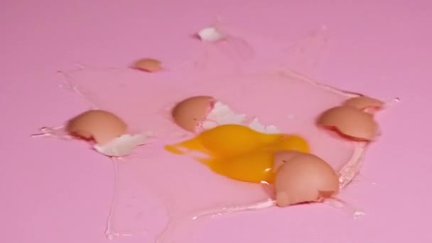 鶏卵が落ちてピンクの背景にブレーキをかけたHdビデオをループします 4K解像度落ちて壊れる卵のスローモーションビデオ — ストック動画