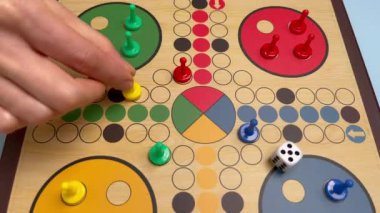 İnsanlar güzel tahta oyun tahtasında Ludo ya da Pachisi oyunu oynuyorlar. Ludo, iki ila dört kişilik bir strateji oyunudur. 4K çözünürlüklü aile oyunu video oyunu.