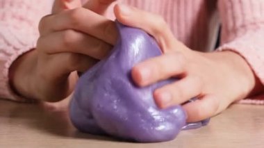 Sümüklü böcek konsepti. Kadın Elleri 'nin tam çözünürlüklü videosu. Kadın elinin mor balçığı tutarken ve sıkarken üst görüntüsü..