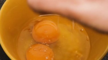 Bir kadın renkli bir kasede çatalla omlet için yumurta çırpıyor ve biraz tuz ekliyor. Kahvaltı ya da omlet yapma kavramı..