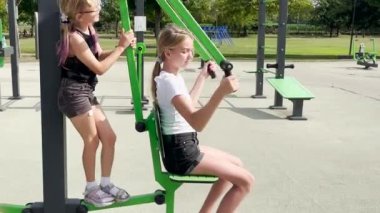 İki kız kardeş spor yapar. Sokakta yaz mevsimi ve çocuklar dışarıda spor salonunda oynuyorlar..