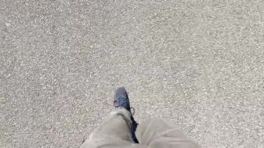 Ayakkabılı bir adamın bacak ve ayaklarının videosu. Tahta bir güvertede yürüyen biri, gün ışığında berrak bir gölge bırakıyor..